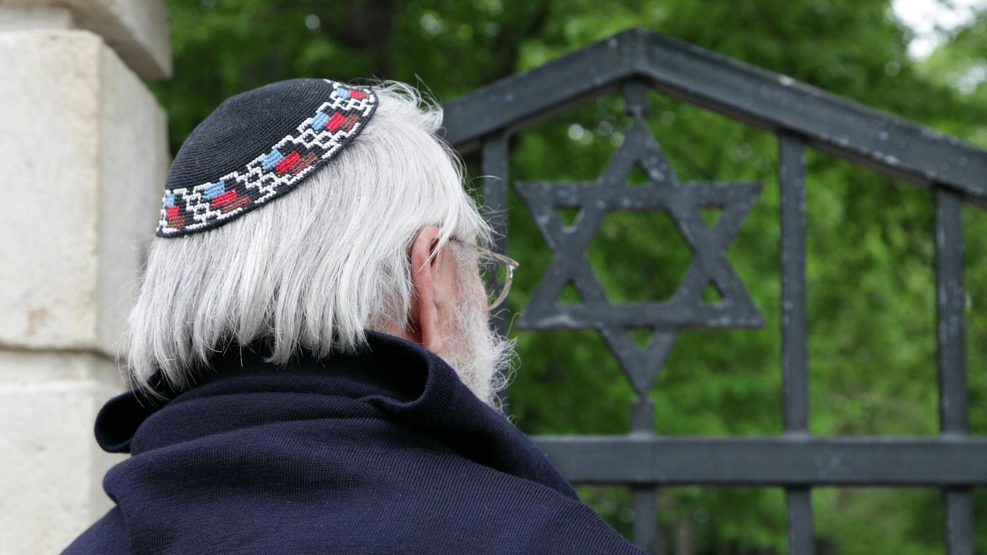 Ein Friedhofsbesucher mit Kippa am Engangstor zum Israelitischen Friedhof in Dessau Ein Friedhofsbesucher mit Kippa am Engangstor zum Israelitischen Friedhof in Dessau