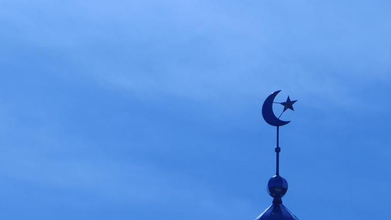 Das Minarett einer Moschee vor blauem Himmel