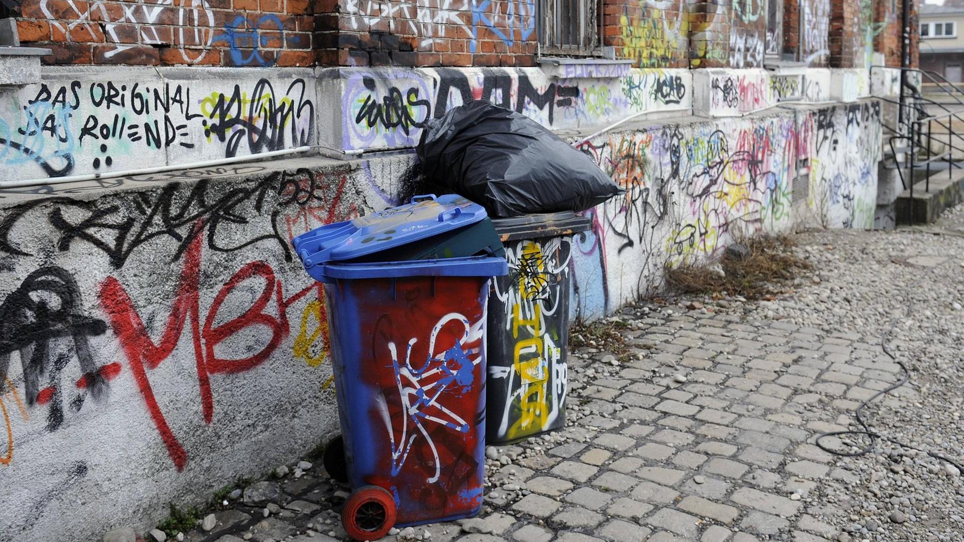 Mit Graffiti besprühte volle Mülltonnen