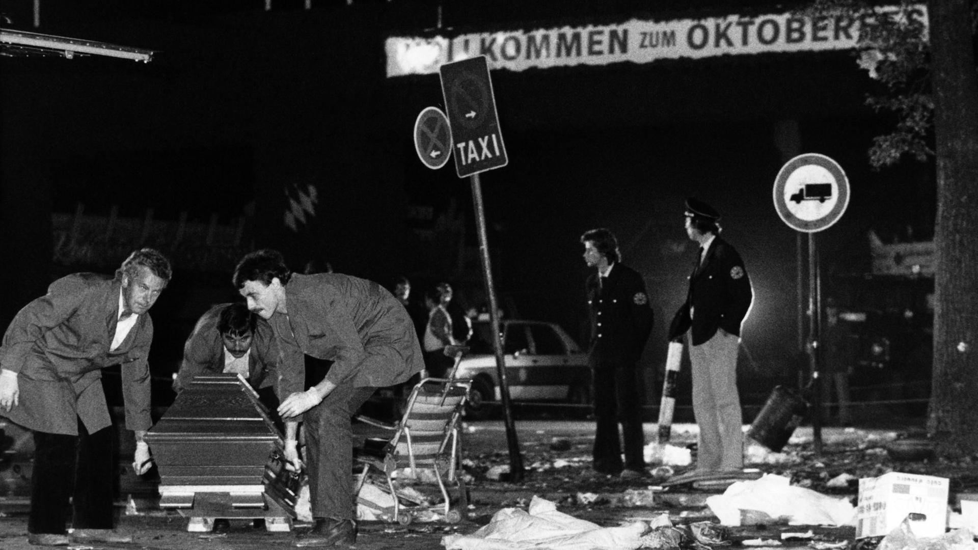 Ein Sarg wird nach dem Bombenanschlag auf dem Münchener Oktoberfest am 26.09.1980 vom verwüsteten Tatort weggetragen. Die Bombe befand sich vermutlich in dem Papierkorb an einem Verkehrsschild rechts im Hintergrund. Ein Sarg wird nach dem Bombenanschlag auf dem Münchener Oktoberfest am 26.09.1980 vom verwüsteten Tatort weggetragen. Die Bombe befand sich vermutlich in dem Papierkorb an einem Verkehrsschild rechts im Hintergrund.