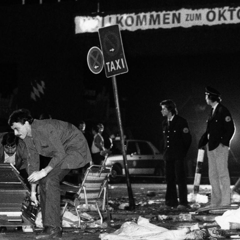 Ein Sarg wird nach dem Bombenanschlag auf dem Münchener Oktoberfest am 26.09.1980 vom verwüsteten Tatort weggetragen. Die Bombe befand sich vermutlich in dem Papierkorb an einem Verkehrsschild rechts im Hintergrund. 