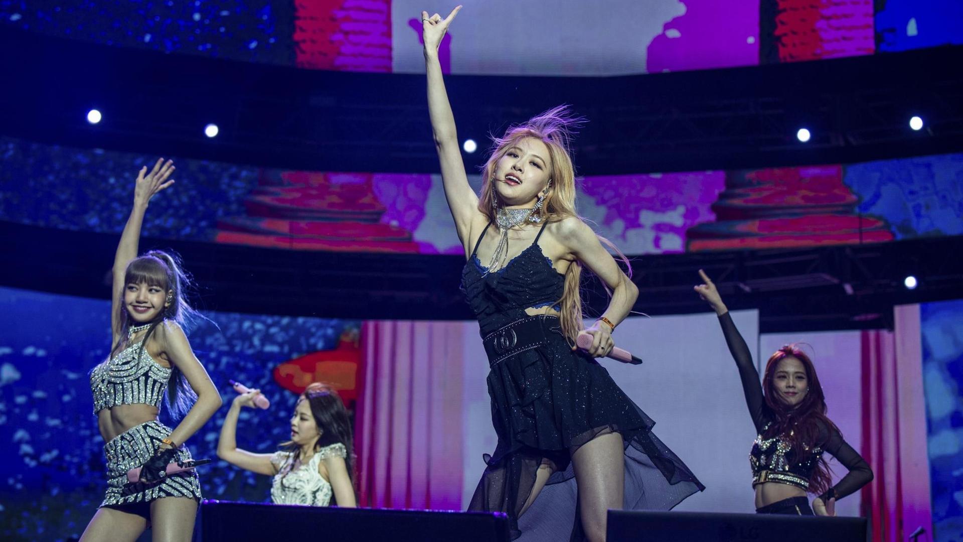Die vier Sängerinnen der Band Blackpink Lisa, Jennie Kim, Rose und Jisoo stehen während eines Auftrittes beim Coachella Festival 2019 in Kalifornien auf der Bühne. Sie tragen Miniröcke und bauchfreie Oberteile, im Hintergrund laufen bunte, überdimensionale Videos. Die vier Sängerinnen der Band Blackpink Lisa, Jennie Kim, Rose und Jisoo stehen während eines Auftrittes beim Coachella Festival 2019 in Kalifornien auf der Bühne. Sie tragen Miniröcke und bauchfreie Oberteile, im Hintergrund laufen bunte, überdimensionale Videos.