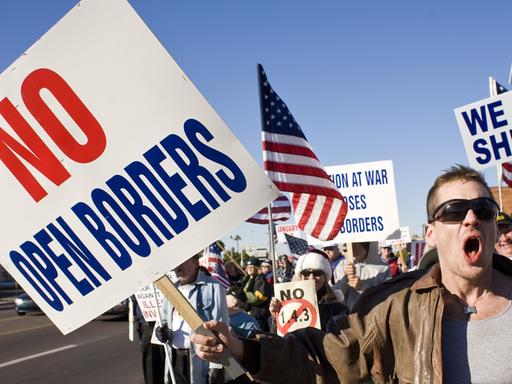 Demonstration in Phoenix gegen Immigration in die USA. "No open borders" steht auf einem Protestplakat, amerikanische Flaggen werden geschwungen.