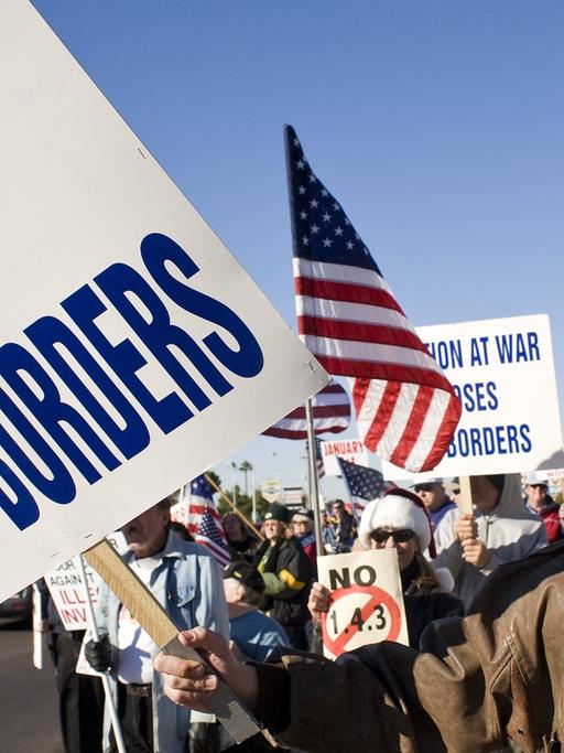 Demonstration in Phoenix gegen Immigration in die USA. "No open borders" steht auf einem Protestplakat, amerikanische Flaggen werden geschwungen.