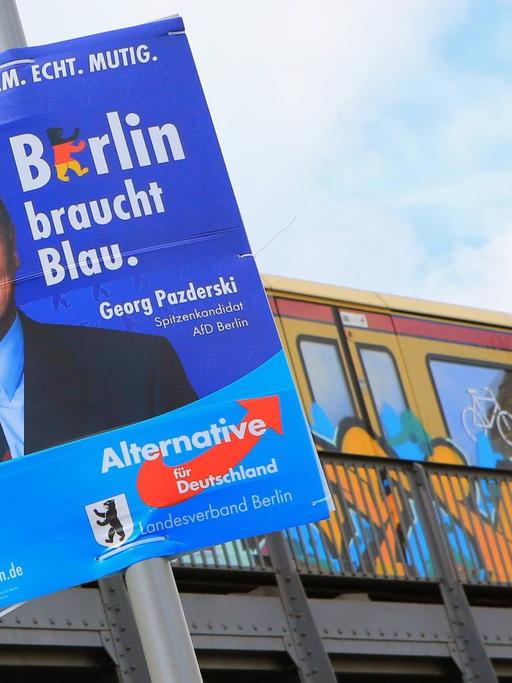 Georg Pazderski, Spitzenkandidat der AfD in Berlin, ist auf einem Wahlplakate zu sehen, das an einem Pfahl vor einer S-Bahn-Strecke hängt.