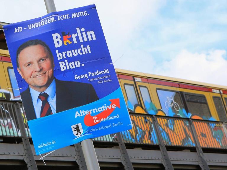 Georg Pazderski, Spitzenkandidat der AfD in Berlin, ist auf einem Wahlplakate zu sehen, das an einem Pfahl vor einer S-Bahn-Strecke hängt.