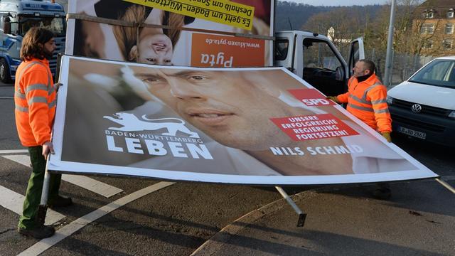 Mitarbeiter eines Werbemittelherstellers bauen ein Wahlplakat mit dem SPD-Spitzenkandidaten Nils Schmid ab
