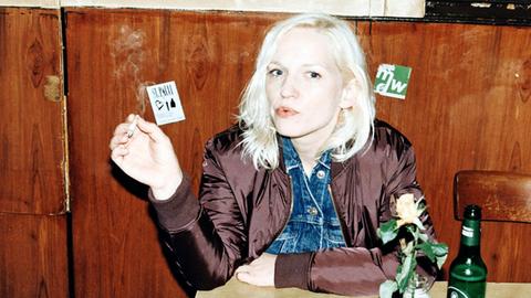 Julia Hummer sitzt mit einer Zigarette in der Hand an einem Kneipentisch.