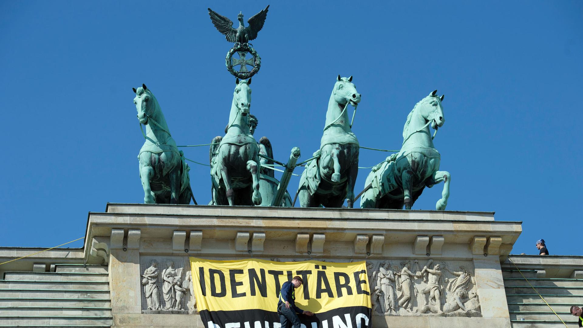 Aktivisten der "Identitären Bewegung" stehen am 27.08.2016 neben der Quadriga auf dem Brandenburger Tor. Die Gruppe wird vom Bundesamt für Verfassungsschutz beobachtet. Sie wendet sich gegen vermeintliche Überfremdung und Islamisierung. Aktivisten der "Identitären Bewegung" stehen am 27.08.2016 neben der Quadriga auf dem Brandenburger Tor. Die Gruppe wird vom Bundesamt für Verfassungsschutz beobachtet. Sie wendet sich gegen vermeintliche Überfremdung und Islamisierung.