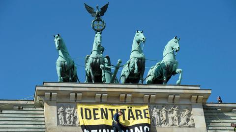 Aktivisten der "Identitären Bewegung" stehen am 27.08.2016 neben der Quadriga auf dem Brandenburger Tor. Die Gruppe wird vom Bundesamt für Verfassungsschutz beobachtet. Sie wendet sich gegen vermeintliche Überfremdung und Islamisierung.