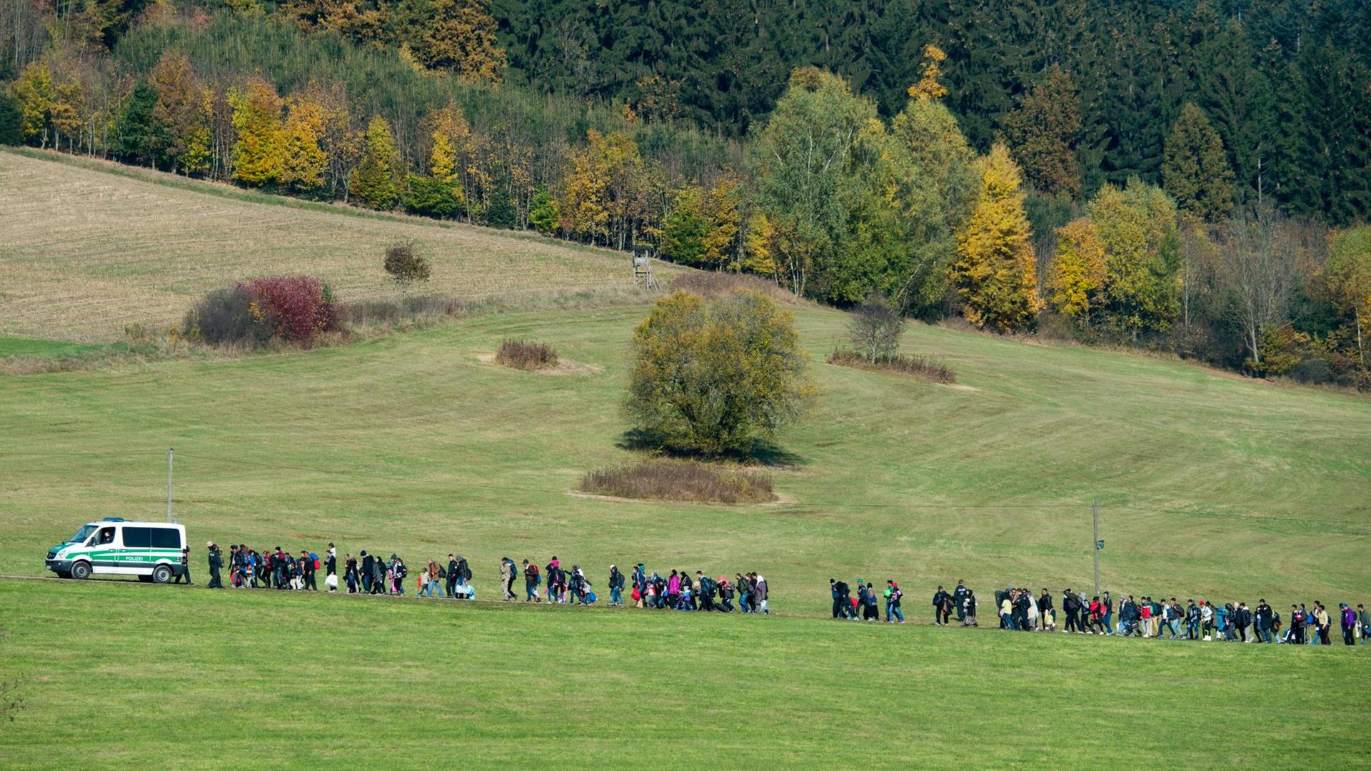 Flüchtlinge gehen nahe der Grenze zu Österreich hinter einem Polizeiwagen her. Flüchtlinge gehen nahe der Grenze zu Österreich hinter einem Polizeiwagen her.
