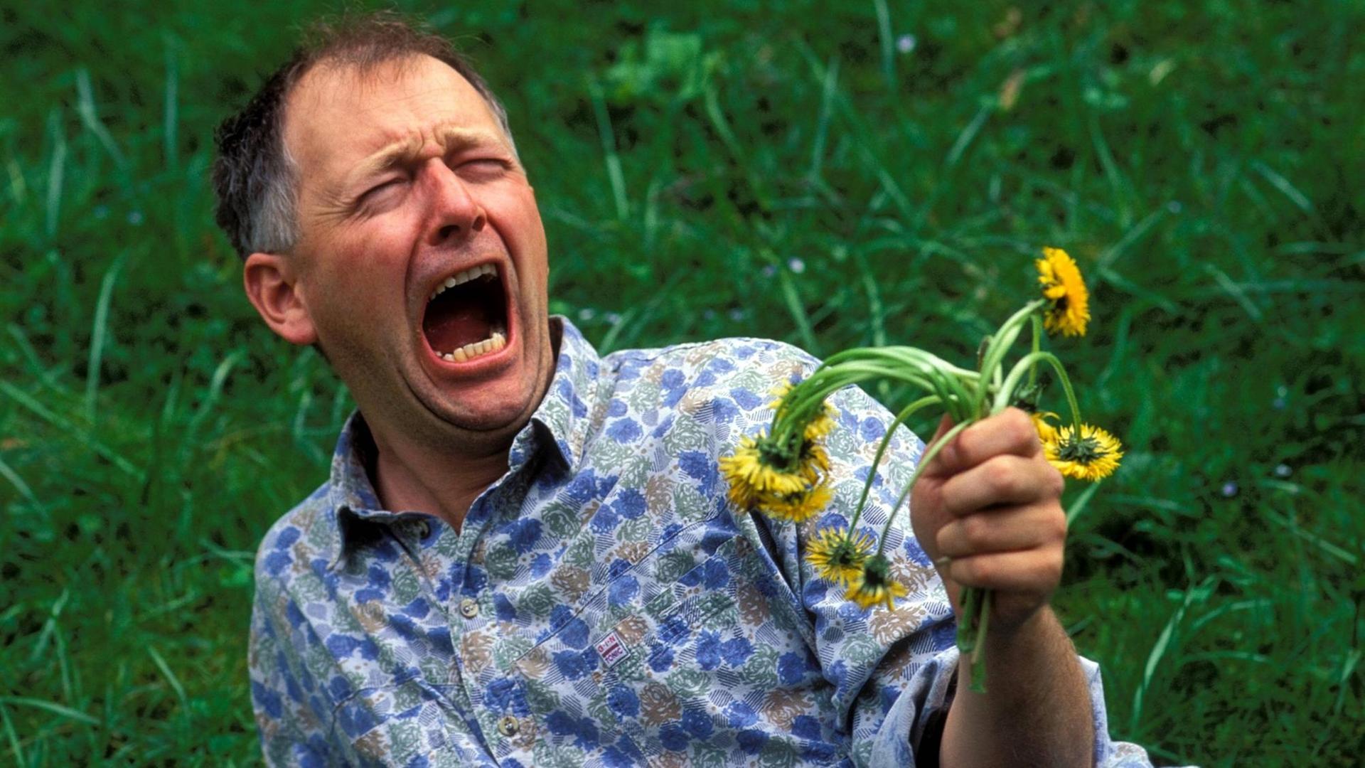 Ein Mann bejammert einen verwelkten Strauß Blumen.