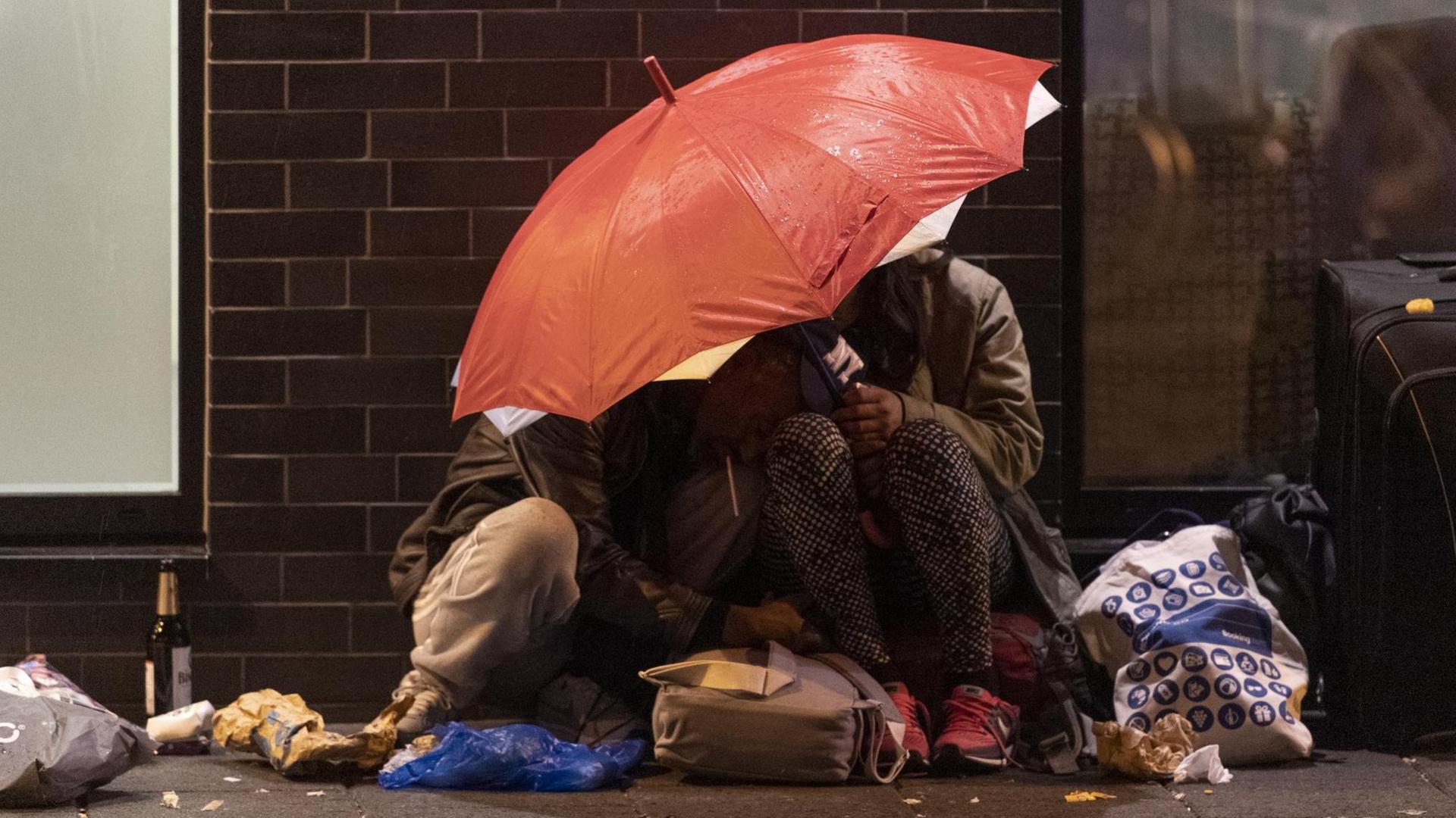 Zwei Menschen haben sich am Rande der Veranstaltung "Bahnhofsviertelnacht" in Frankfurt am Main unter einen Regenschirm zurückgezogen. Zwei Menschen haben sich am Rande der Veranstaltung "Bahnhofsviertelnacht" in Frankfurt am Main unter einen Regenschirm zurückgezogen.