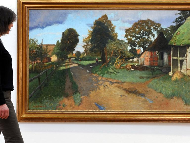 Antje Modersohn, Enkelin des Worpsweder Malers Otto Modersohn, vor dem Gemälde "Dorfstraße in Worpswede".
