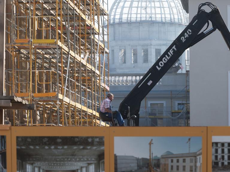 Ein Arbeiter sitzt am 13.9.2016 in Berlin vor der Kulisse der Kuppel des Stadtschlosses neben dem Baugerüst an der Staatsoper Unter den Linden.