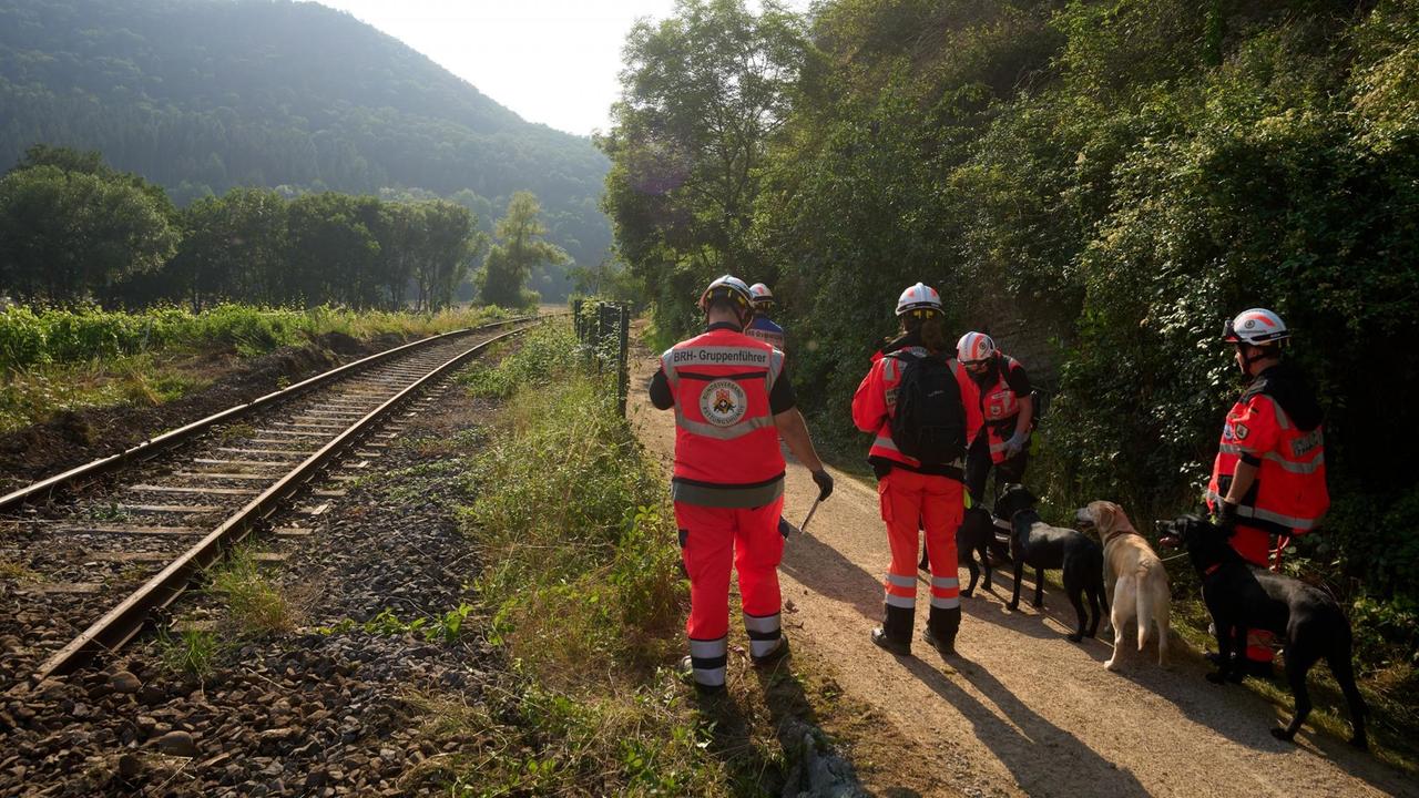 Rheinland-Pfalz, Rech: Hundeführer suchen nahe der Ortschaft nach dem Hochwasser nach Vermissten.