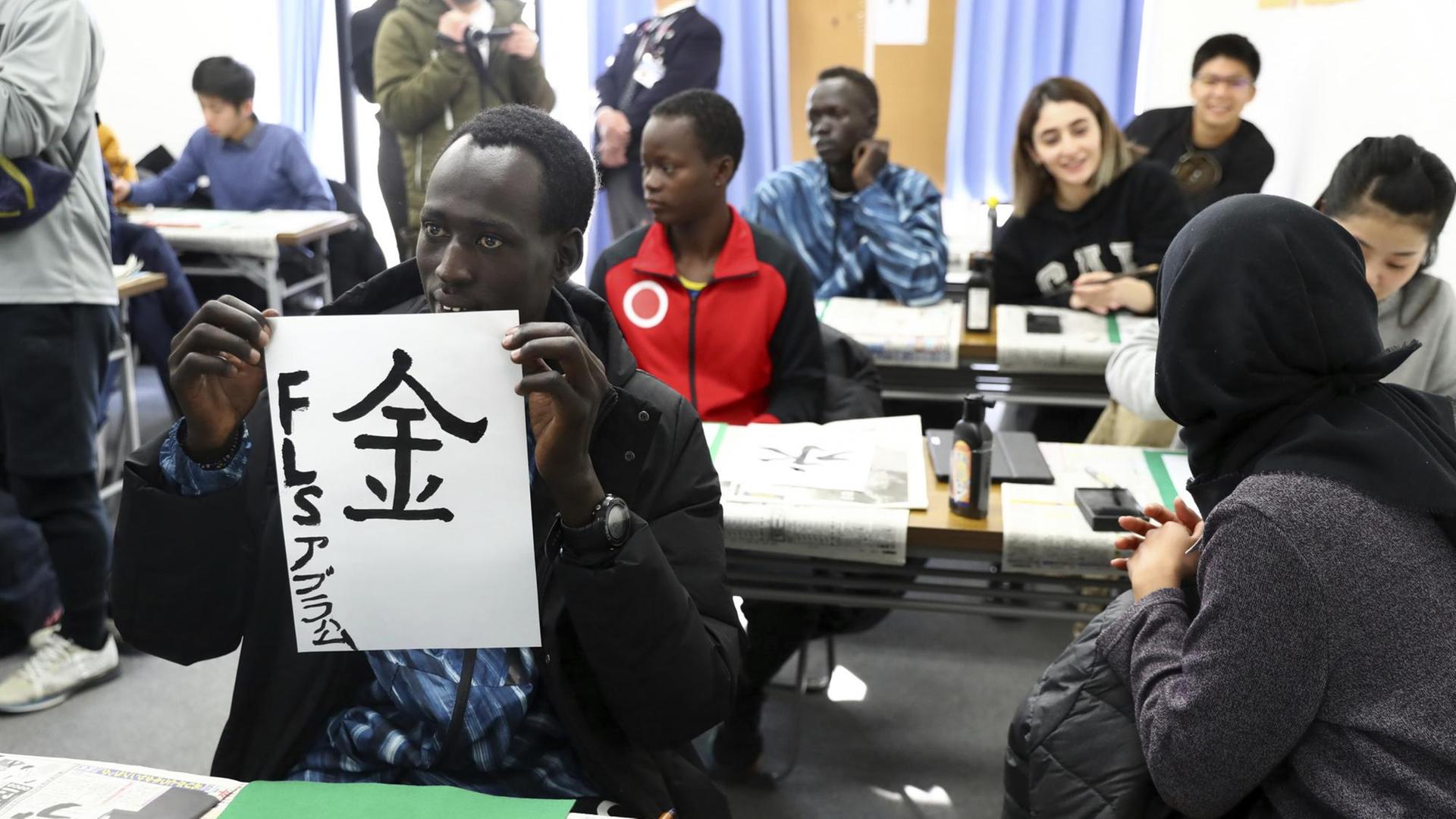 Die südsudanesischen Athleten und Athletinnen üben japanische Schriftzeichen. Die südsudanesischen Athleten und Athletinnen üben japanische Schriftzeichen.