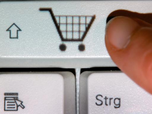 Ein Finger zeigt auf das Symbol eines Einkaufwagens auf einer Taste einer Computertastatur. 