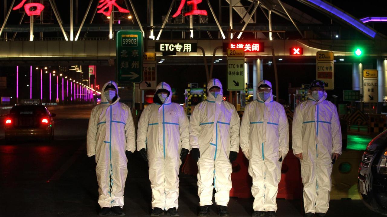 Polizisten in Schutzanzügen kontrollieren die Zufahrt zur aufgrund der Corona-Pandemie abgeriegelten chinesischen Stadt Shijiazuang. 