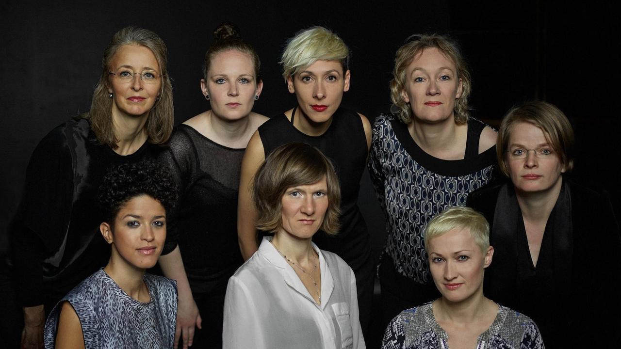 Acht Frauen stehen dicht beieinander und schauen ernst in die Kamera. Acht Frauen stehen dicht beieinander und schauen ernst in die Kamera.