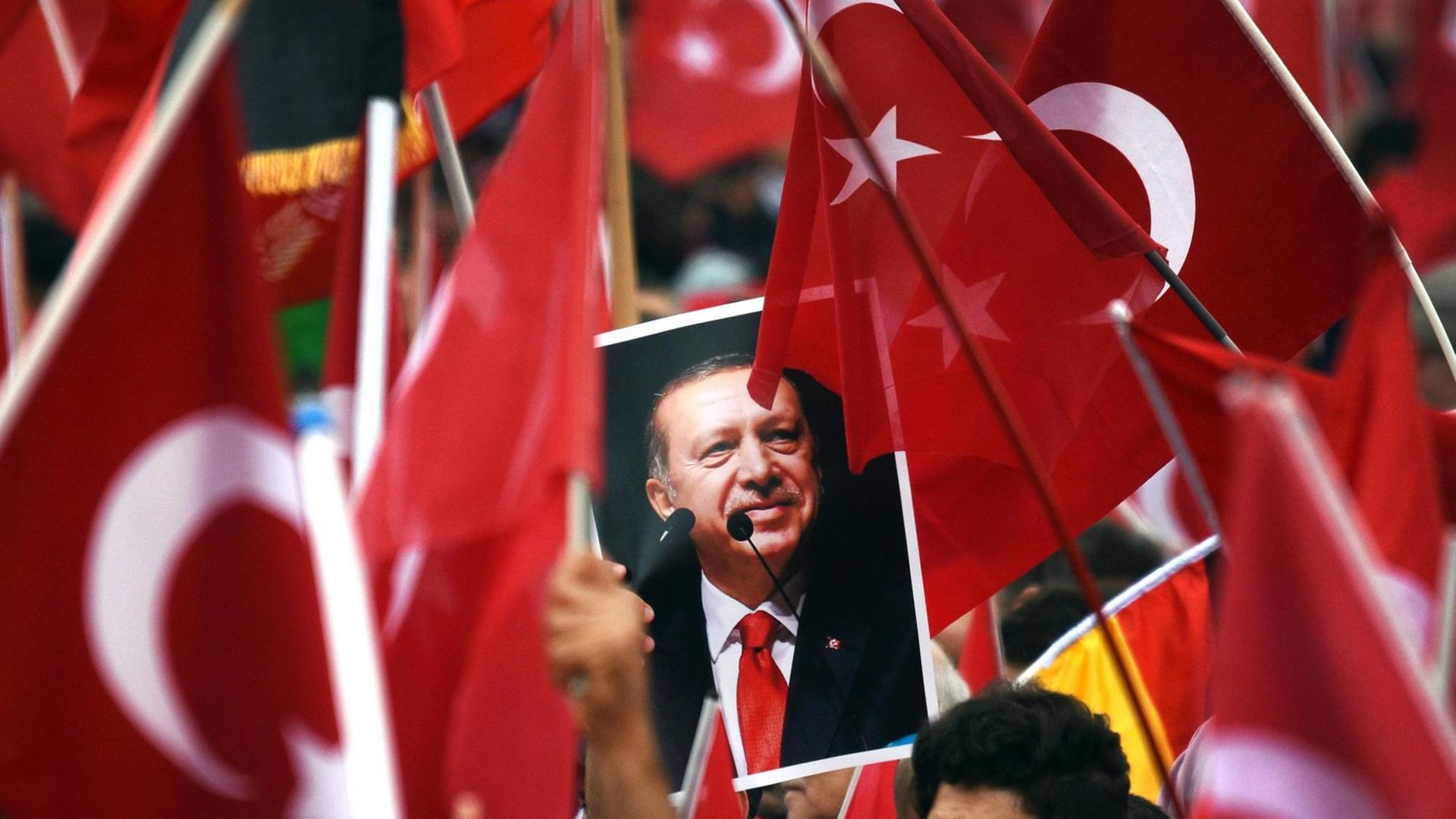 Anhänger des türkischen Staatspräsidenten Recep Tayyip Erdogan halten in Köln Fahnen und ein Bild des Staatschefs. Anhänger des türkischen Staatspräsidenten Recep Tayyip Erdogan halten in Köln Fahnen und ein Bild des Staatschefs.