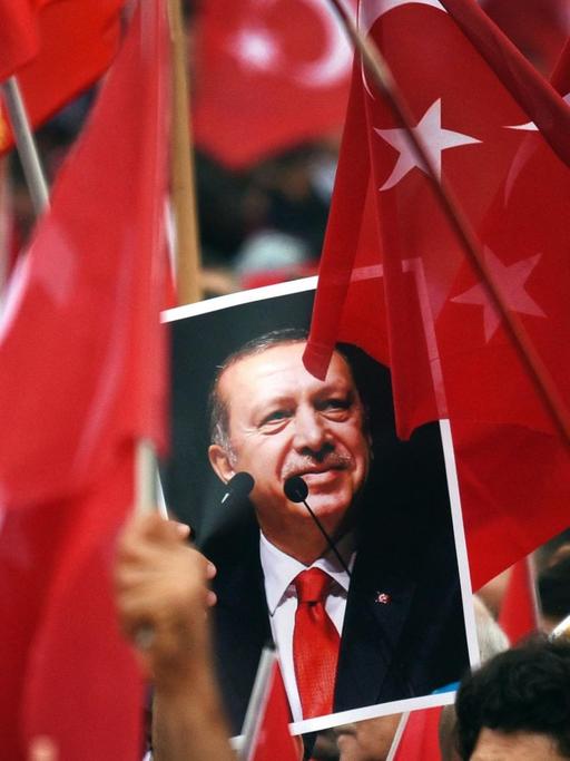 Anhänger des türkischen Staatspräsidenten Recep Tayyip Erdogan halten in Köln Fahnen und ein Bild des Staatschefs.