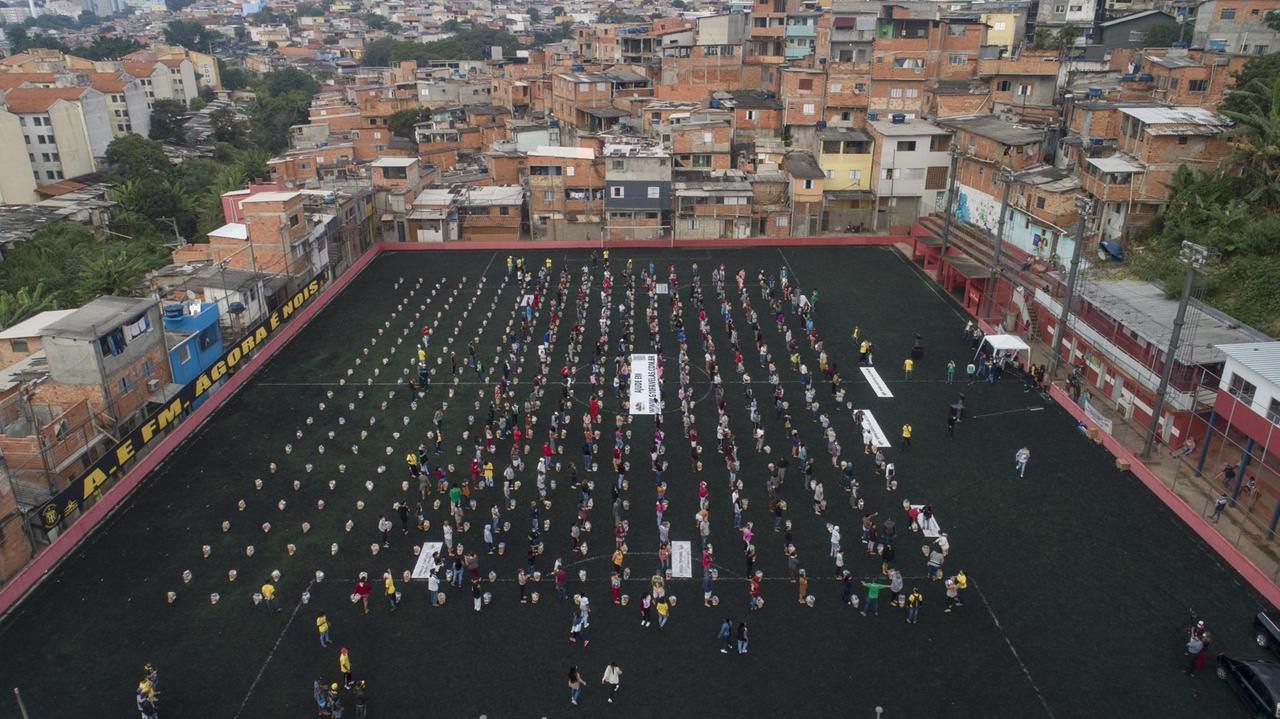 Bewohner warten in Corona-Abstand in einem Fußball-Stadion in Sao Paulo in Brasilien auf eine Essens-Spende am 26.04.2021. 