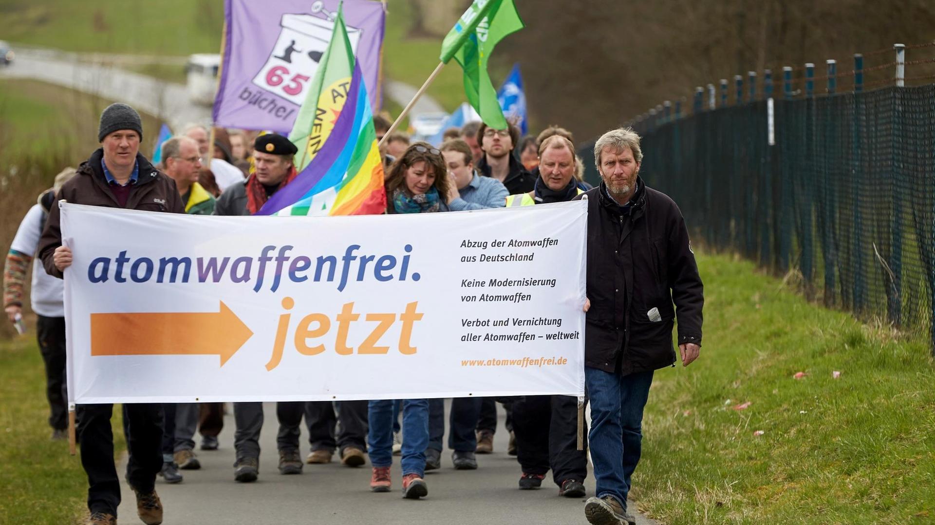 Teilnehmer des Ostermarschs am Fliegerhorst Büchel laufen am 06.04.2015 am Außenzaun des Luftwaffen-Fliegerhorsts in Büchel vorbei.Sie demonstrieren für den Abzug der dort gelagerten amerikanischen Atomwaffen. Foto: Thomas Frey/dpa Teilnehmer des Ostermarschs am Fliegerhorst Büchel laufen am 06.04.2015 am Außenzaun des Luftwaffen-Fliegerhorsts in Büchel vorbei.Sie demonstrieren für den Abzug der dort gelagerten amerikanischen Atomwaffen. Foto: Thomas Frey/dpa