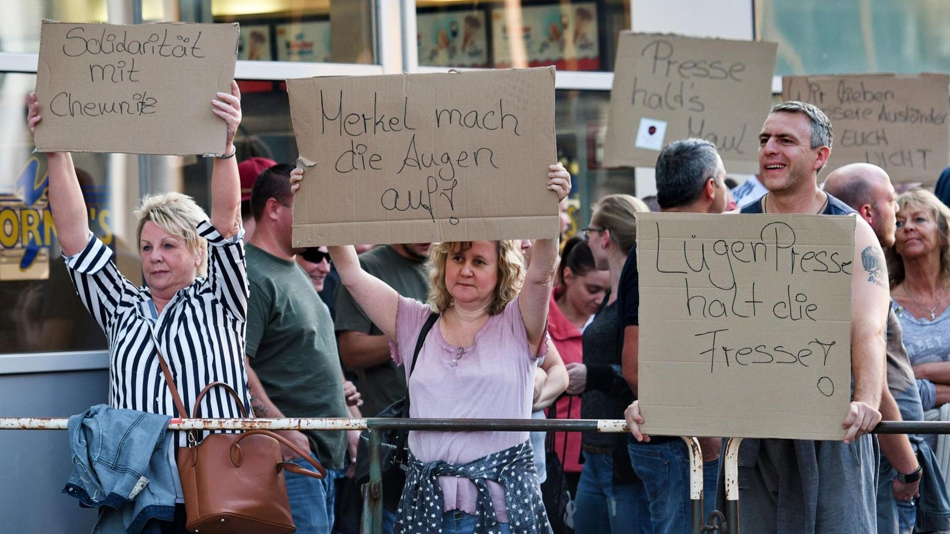 Teilnehmer einer Kundgebung rechter Gruppen halten Plakate hoch. Teilnehmer einer Kundgebung rechter Gruppen halten Plakate hoch.