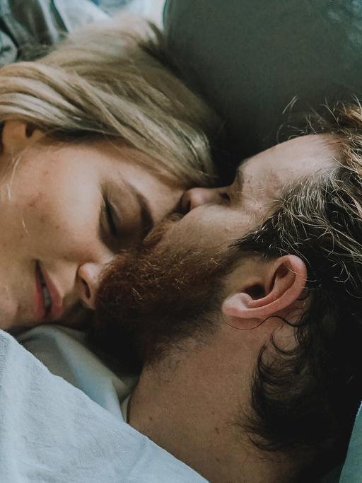 Ein Mann und eine Frau liegen im Bett und umarmen sich.