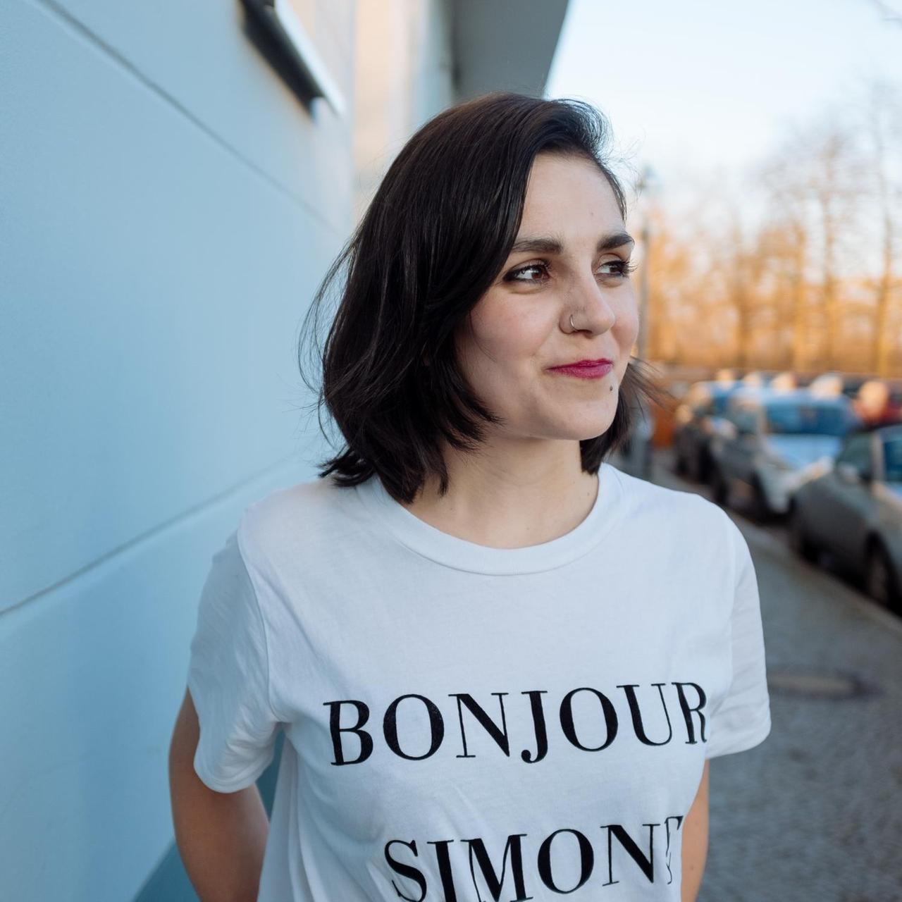 Die Journalistin und Autorin Julia Korbik trägt ein T-Shirt auf dem "Bonjour Simone" steht