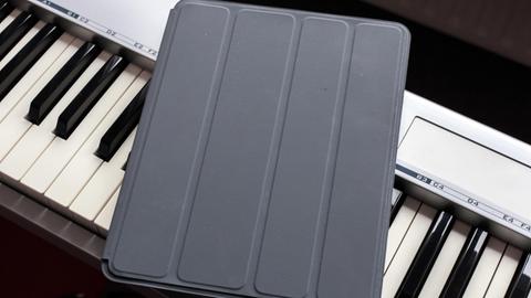Das Bild zeigt ein iPad auf einer Klavier-Tastatur.