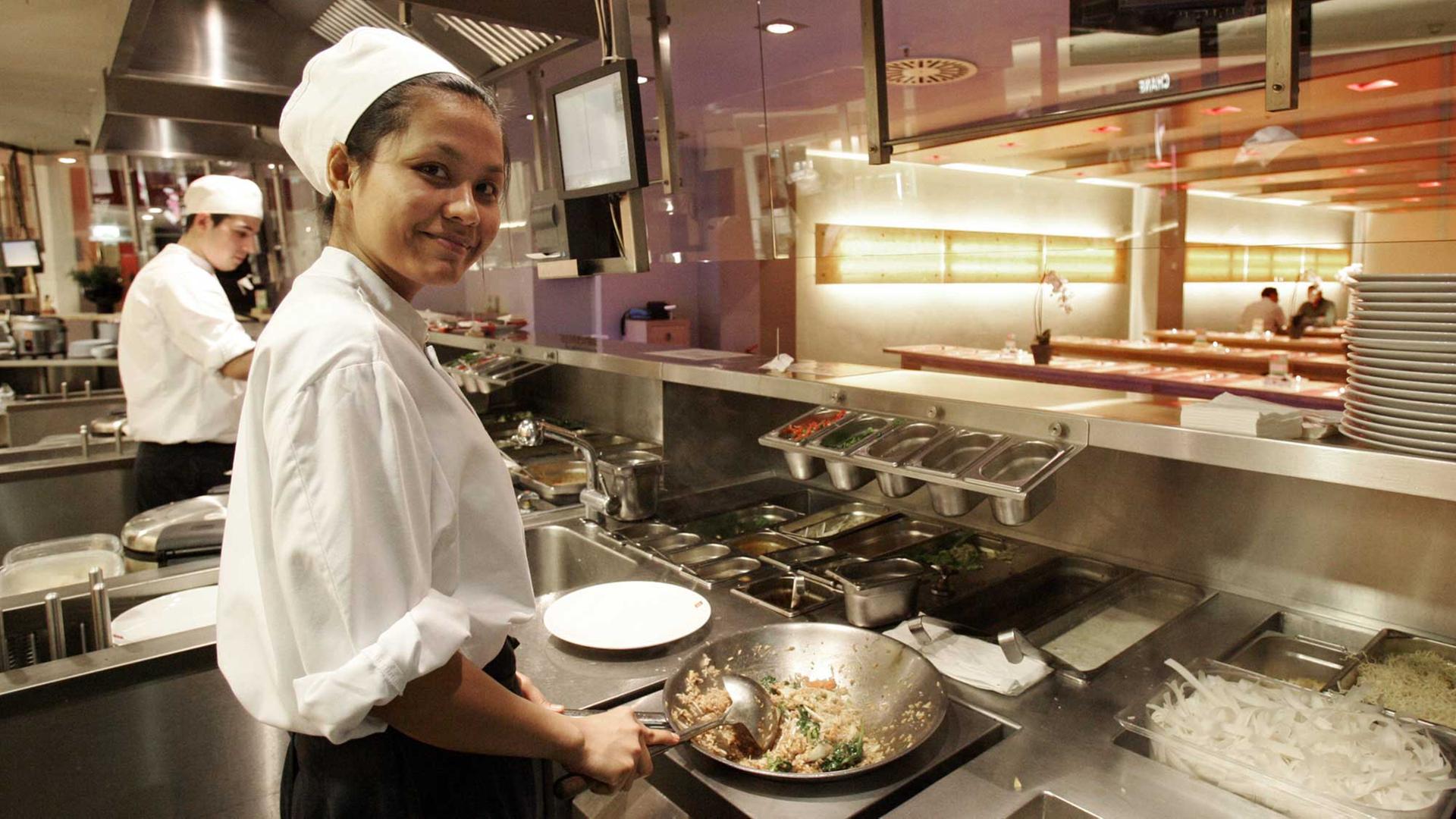 Eine Köchin rührt im Schnell-Restaurant "Cha Cha" in Hamburg den Wok auf einem Induktionsherd. Eine Köchin rührt im Schnell-Restaurant "Cha Cha" in Hamburg den Wok auf einem Induktionsherd.