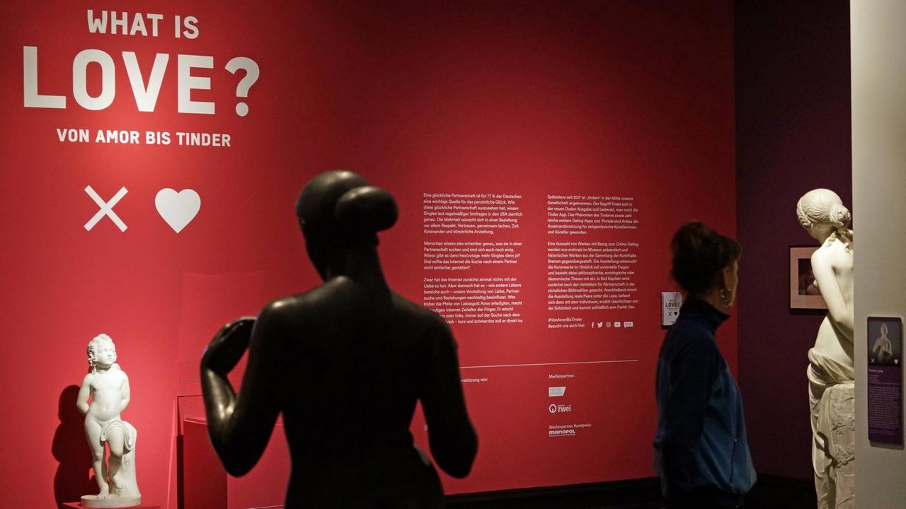 Blick in die Sonderausstellung der Kunsthalle Bremen "What is Love? Von Amor bis Tinder." veranstaltet vom 7. Juli bis 21. Oktober 2018. Die Exponate befassen sich mit Liebe, Partnerschaft, Erotik, Schönheit und Narzissmus und behandeln auch das Online-Dating mit der App Tinder. Im Vordergrund eine Skulptur von Adolf Steinhäuser (ohne Jahresangabe), die den Liebesgott Amor darstellt. Blick in die Sonderausstellung der Kunsthalle Bremen "What is Love? Von Amor bis Tinder." veranstaltet vom 7. Juli bis 21. Oktober 2018. Die Exponate befassen sich mit Liebe, Partnerschaft, Erotik, Schönheit und Narzissmus und behandeln auch das Online-Dating mit der App Tinder. Im Vordergrund eine Skulptur von Adolf Steinhäuser (ohne Jahresangabe), die den Liebesgott Amor darstellt.