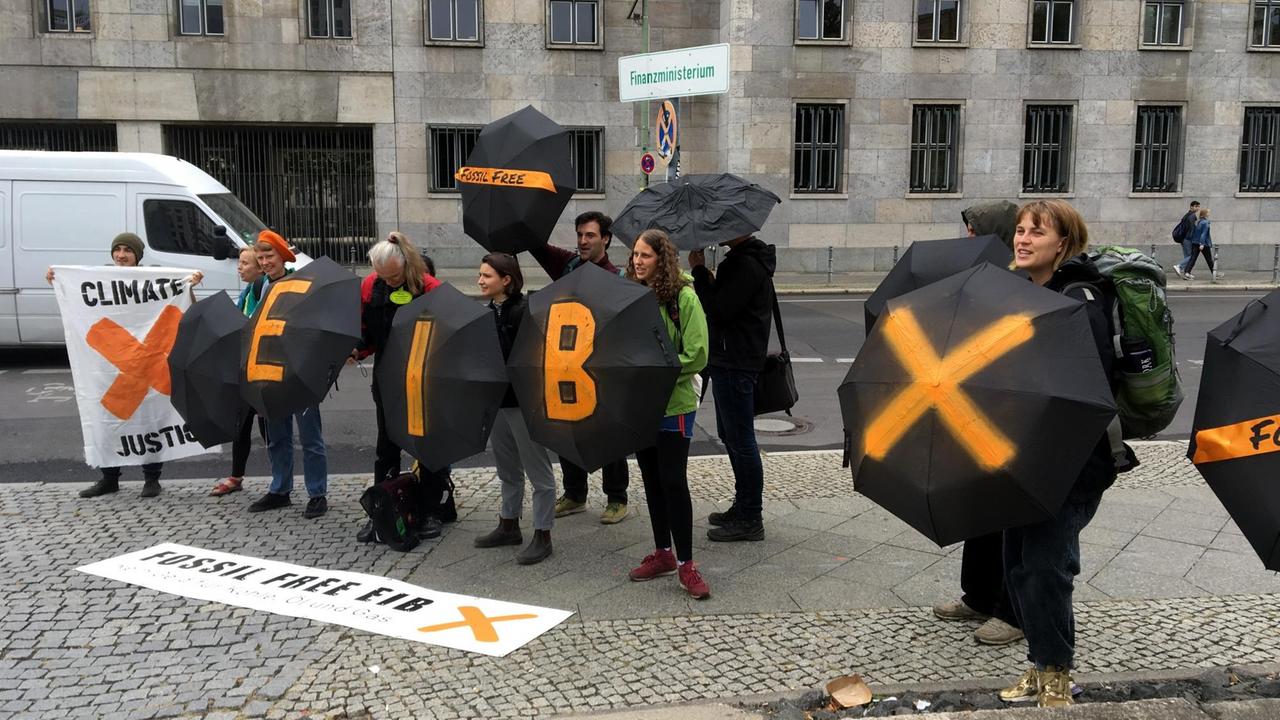 Protestierende in Schwarz mit beschriebenen Regenschirmen stehen vor dem Finanzministerium. Protestierende in Schwarz mit beschriebenen Regenschirmen stehen vor dem Finanzministerium.