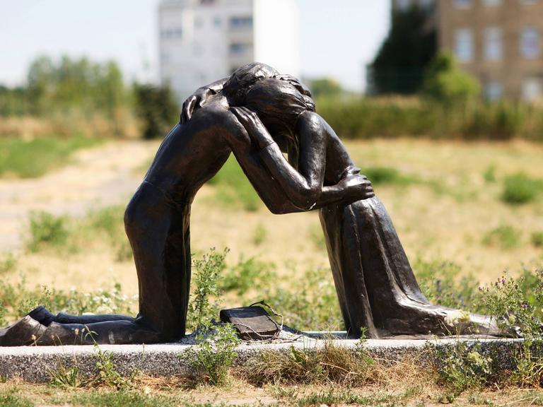 Zwei Knieende, Mann und Frau, die sich umarmen - Skulptur "Versöhnung" an der Versöhnungskapelle in der Bernauer Straße in Berlin
