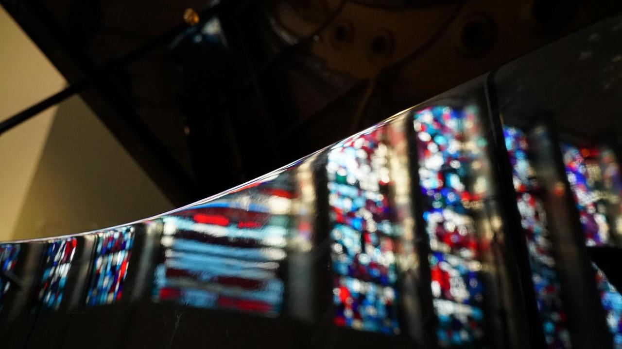 Bunte Kirchenfensterspiegelungen zeigen sich auf einem aufgeklappten Flügel. Bunte Kirchenfensterspiegelungen zeigen sich auf einem aufgeklappten Flügel.