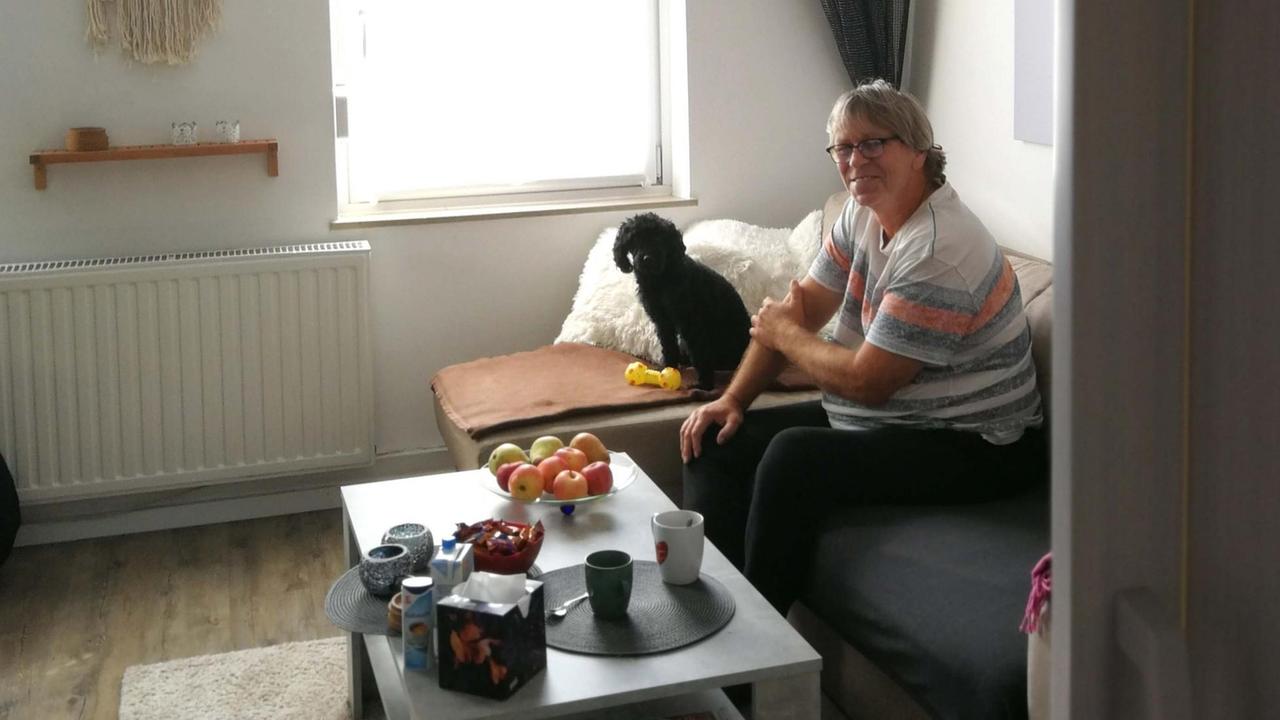 Ein Mann und ein Hund sitzen in einem Wohnzimmer auf einem Sofa. Ein Mann und ein Hund sitzen in einem Wohnzimmer auf einem Sofa.