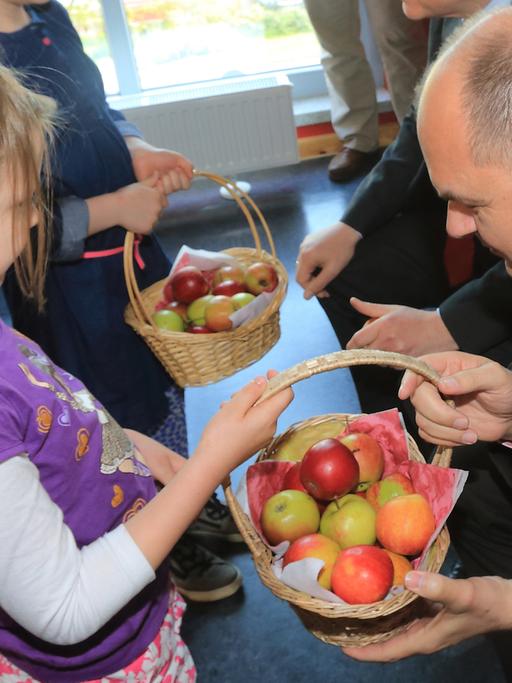 Ein Korb mit frischen Äpfeln wird an einer Grundschule an Kinder verteilt.