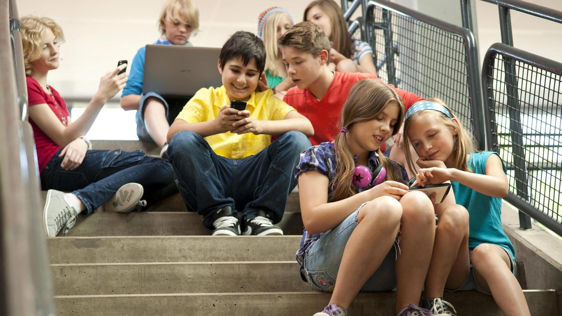 Gruppe Schüler sitzt auf einer Treppe und kommuniziert mit Tablet-PCs und Smartphones | Verwendung weltweit, Keine Weitergabe an Wiederverkäufer. | dpa / picture alliance / imageBROKER Gruppe Schüler sitzt auf einer Treppe und kommuniziert mit Tablet-PCs und Smartphones | Verwendung weltweit, Keine Weitergabe an Wiederverkäufer. | dpa / picture alliance / imageBROKER