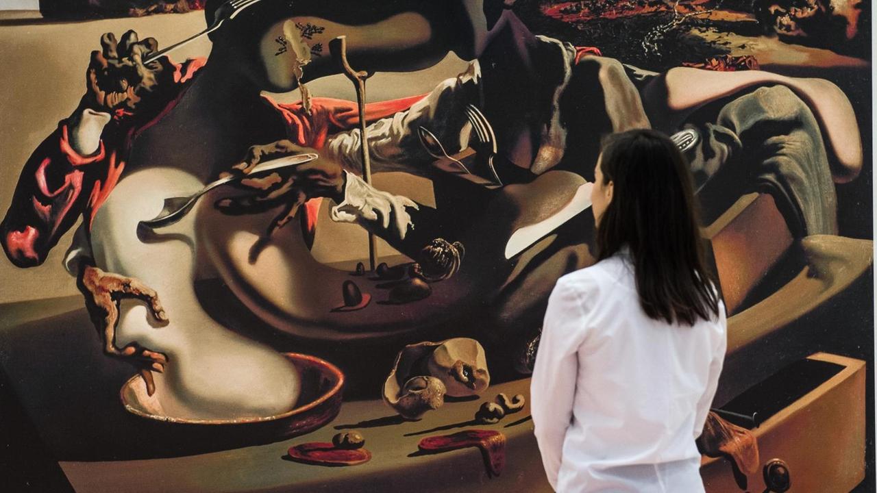 Eine Frau schaut sich die Wandtapete "Autumnal Cannibalism, 1936" des Künstlers Salvador Dali an. Eine Frau schaut sich die Wandtapete "Autumnal Cannibalism, 1936" des Künstlers Salvador Dali an.