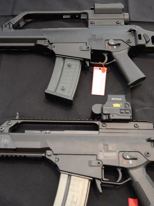 Zwei Sturmgewehre G36 von Heckler und Koch liegen am 07.05.2015 in Oberndorf in der Firmenzentrale auf einem Tisch vor einem Logo des Waffenproduzenten.