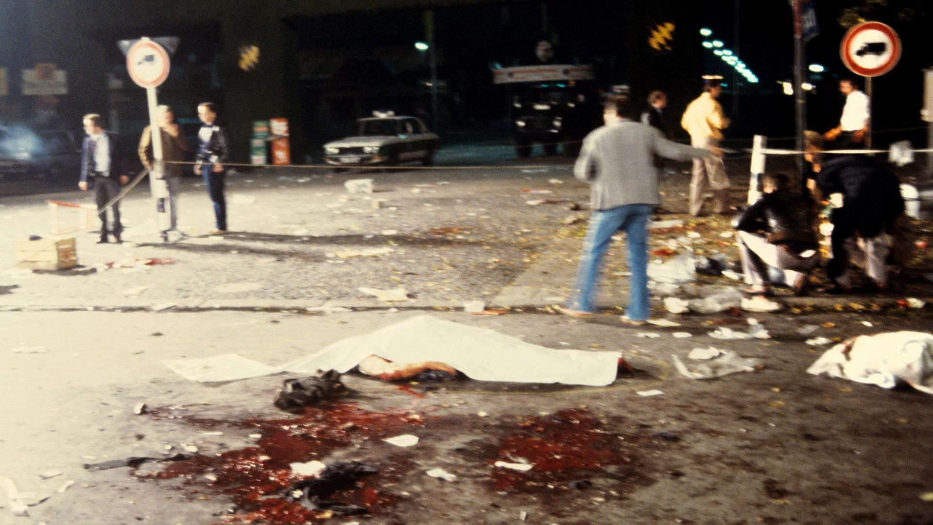 Mit Tüchern zugedeckte Todesopfer liegen neben Blutlachen am Tatort des nächtlichen Anschlages auf dem Münchner Oktoberfest am 26.9.1980. Mit Tüchern zugedeckte Todesopfer liegen neben Blutlachen am Tatort des nächtlichen Anschlages auf dem Münchner Oktoberfest am 26.9.1980.