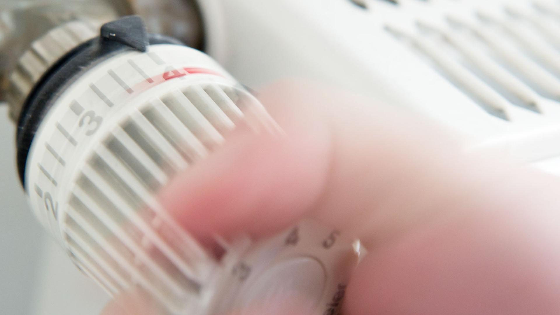 Jemand dreht an einem Thermostat eines Heizkörpers. Jemand dreht an einem Thermostat eines Heizkörpers.