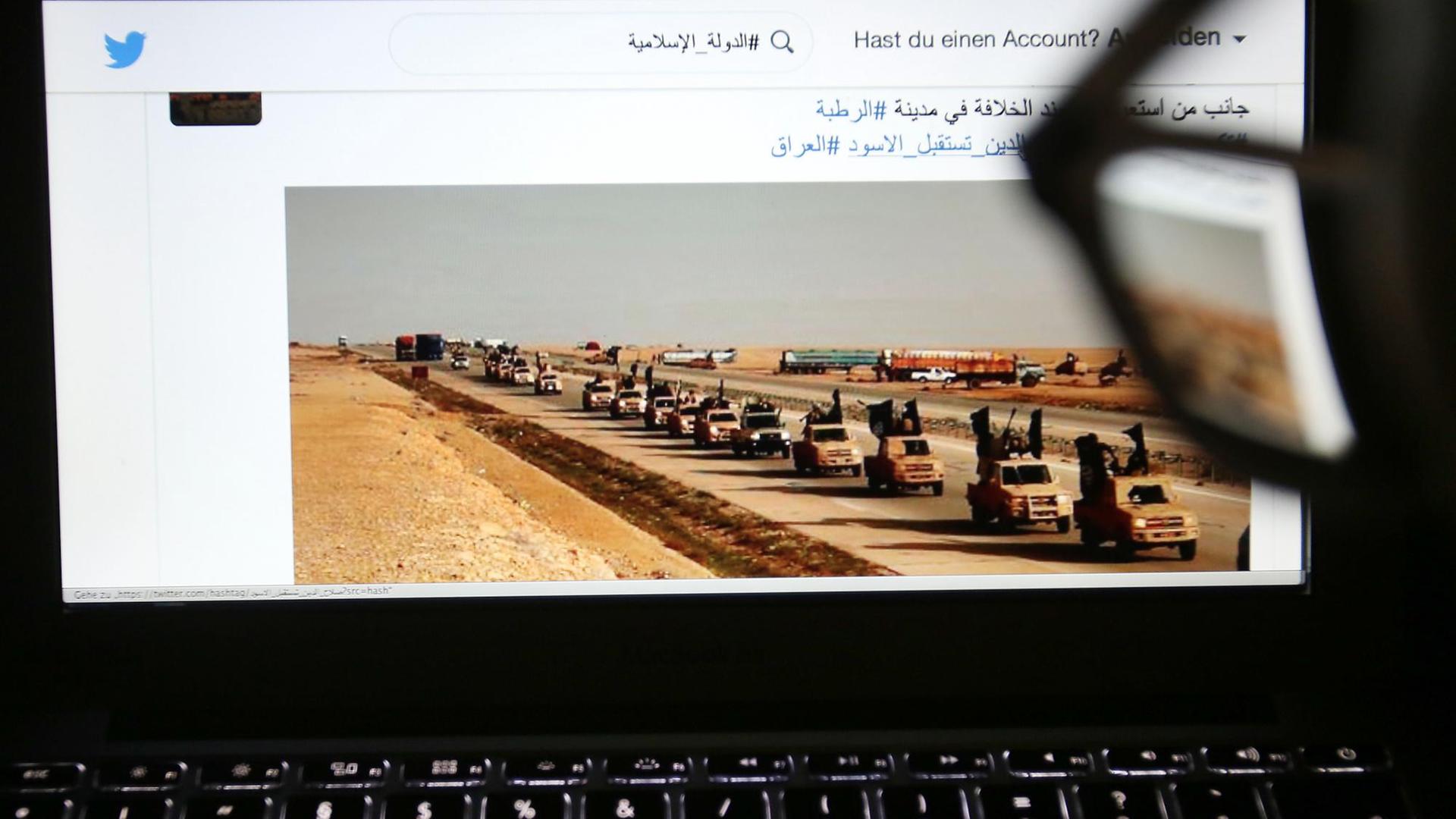 Eine junge Frau schaut in Köln auf einen Computermonitor, auf dem einer Website mit Propaganda des IS zu sehen ist.