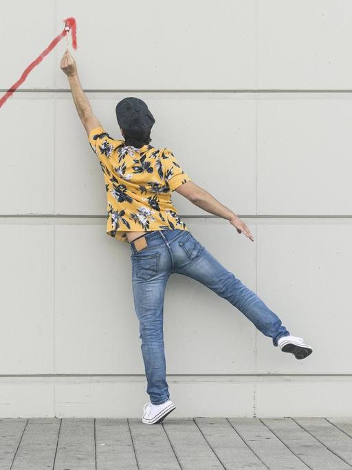 Ein Mann malt eine aufsteigende Linie an eine Wand.