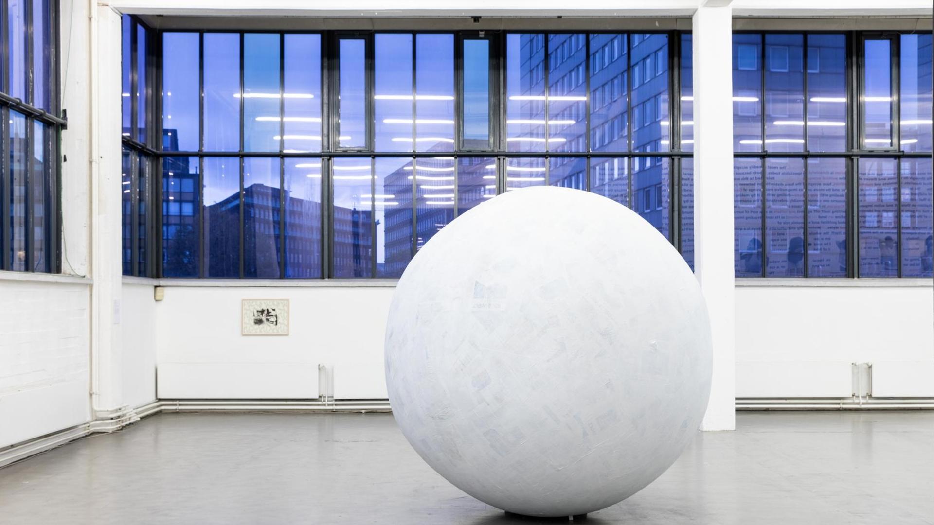 Ein weiße, große Kugel steht vor den nachtblauen Fenstern des Kunstvereins Hamburg