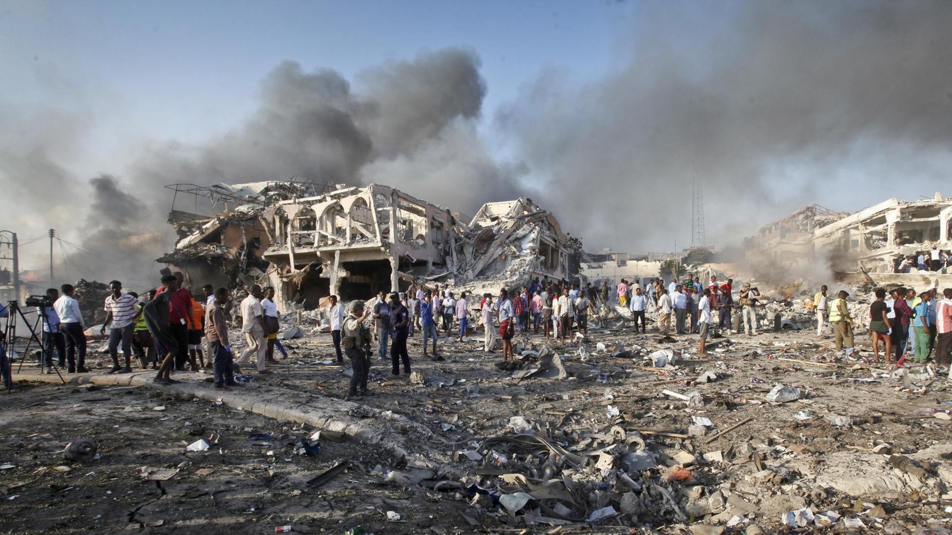 Menschen suchen am in Mogadischu (Somalia) nach einem Selbstmordanschlag in den Trümmern eines Hauses nach Überlebenden. Über ihnen sind Rauchsäulen ztu sehen. Menschen suchen am in Mogadischu (Somalia) nach einem Selbstmordanschlag in den Trümmern eines Hauses nach Überlebenden. Über ihnen sind Rauchsäulen ztu sehen.
