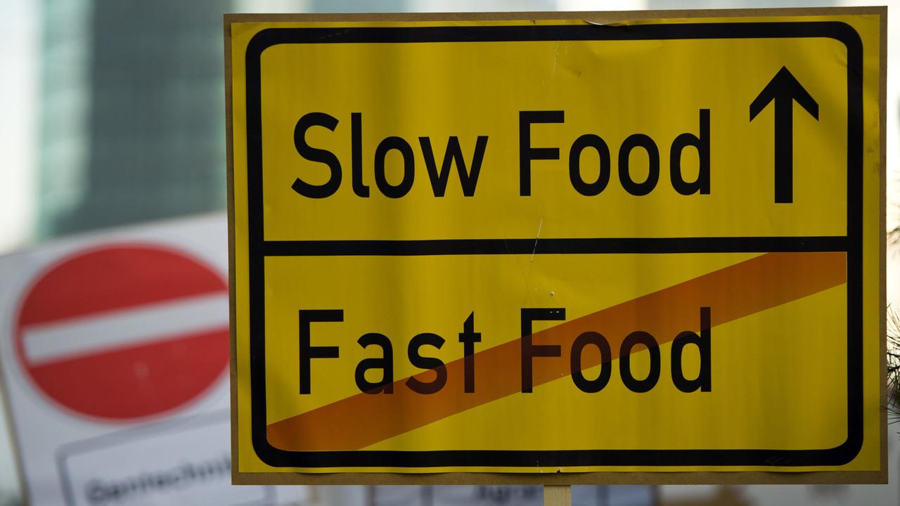 Ein Schild mit der Aufschrift "Slow Food - Fast Food" ist in Berlin auf einer Demonstration zu sehen. Ein Schild mit der Aufschrift "Slow Food - Fast Food" ist in Berlin auf einer Demonstration zu sehen.