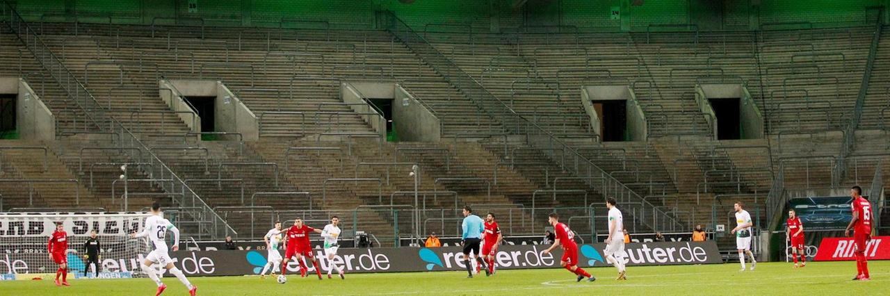 Borussia Mönchengladbach und der 1. FC Köln spielen im Borussia-Park vor leeren Zuschauerrängen. Im Vordergrund spielen sie Mannschaften gegeneinander. Im Hintergrund sind sie leeren Ränge zu sehen. Borussia Mönchengladbach und der 1. FC Köln spielen im Borussia-Park vor leeren Zuschauerrängen. Im Vordergrund spielen sie Mannschaften gegeneinander. Im Hintergrund sind sie leeren Ränge zu sehen.